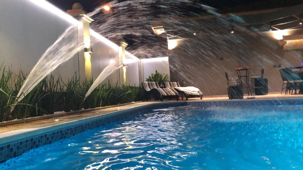 Área de lazer com piscina iluminada à noite, projeto da Farão Arquitetura