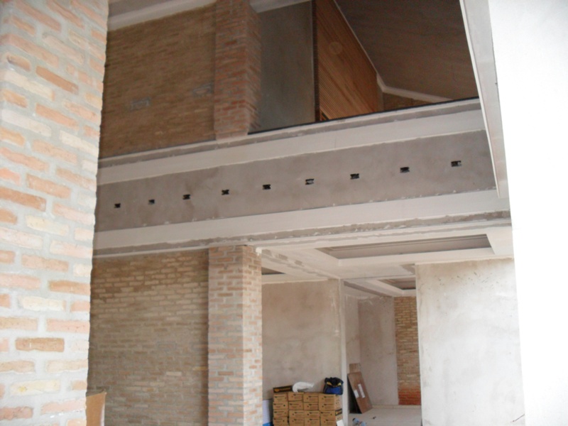 Mezanino e vigas aparentes - Vazio central com mezanino, viga de concreto aparente e alvenaria em tijolo à vista.